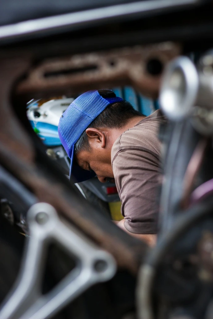 Man wearing a blue cap working on a vehicle.